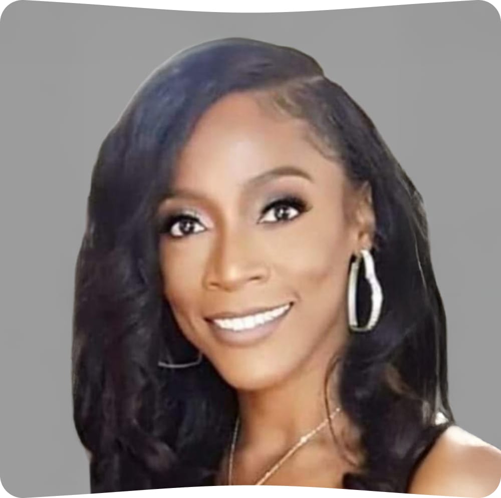 Smiling woman with long, wavy black hair, wearing hoop earrings and a necklace, in front of a plain gray background.